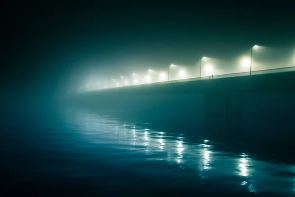 A beautiful evening fog above the river in city centre. Bridge in the mist, autumn scenery. Soft, blurry, misty look. Colorful, mystic cityscape of Riga, Latvia. — Stock Photo, Image