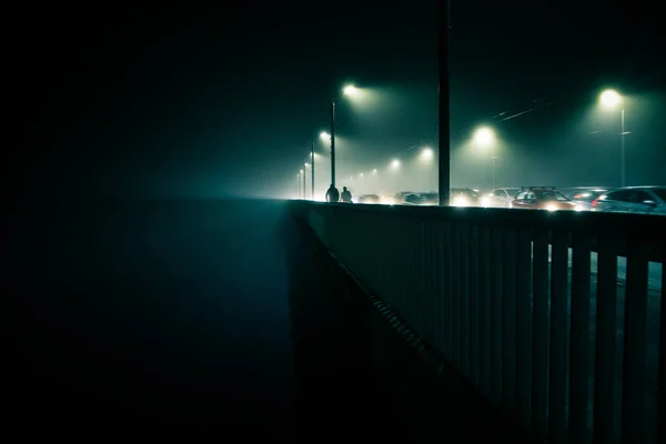 Una hermosa niebla nocturna sobre el río en el centro de la ciudad. Puente en la niebla, paisaje otoñal. Mirada suave, borrosa y brumosa. Colorido paisaje urbano místico de Riga, Letonia . — Foto de Stock