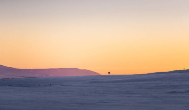 Güzel renkli kış günbatımı Merkez Norveç'te. Dağların üzerinden sıcak akşam ışığı.