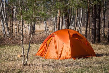 Nehir kıyısında inşa turuncu bir çadır. Baharda kamp hiking. Erken Bahar sahne.