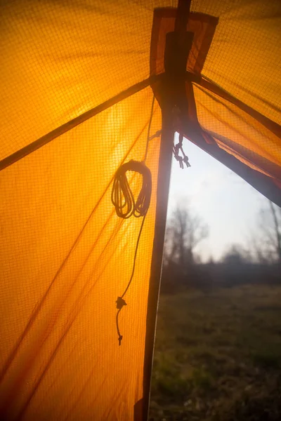 A look through the entrance of the tent. Orange camping tent in an early spring. Exit door.