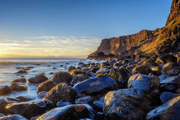 Talisker Bay kayalar ve kayalıklarla gün batımında