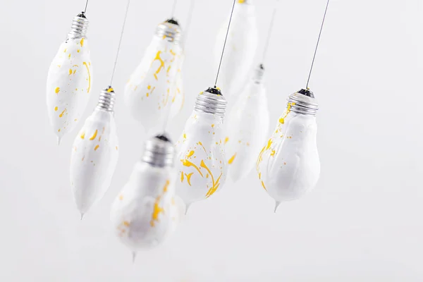 Bílé světlo žárovky s žlutý sprej na bílém pozadí — Stock fotografie