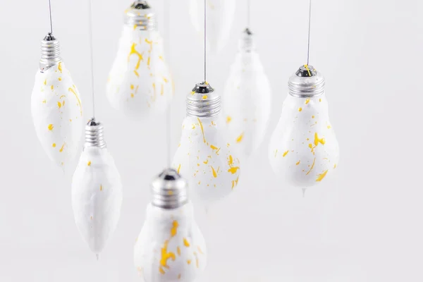 White light bulbs with yellow spray on a white background