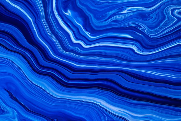 Fluid art texture. Background with abstract swirling paint effect. Liquid acrylic artwork with flows and splashes. Classic blue color of the year 2020. Blue, white and indigo overflowing colors.