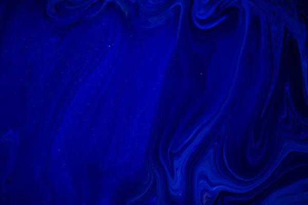 Fluid art texture. Backdrop with abstract swirling paint effect. Liquid acrylic picture that flows and splashes. Classic blue color of the year 2020. Blue, black and white overflowing colors.