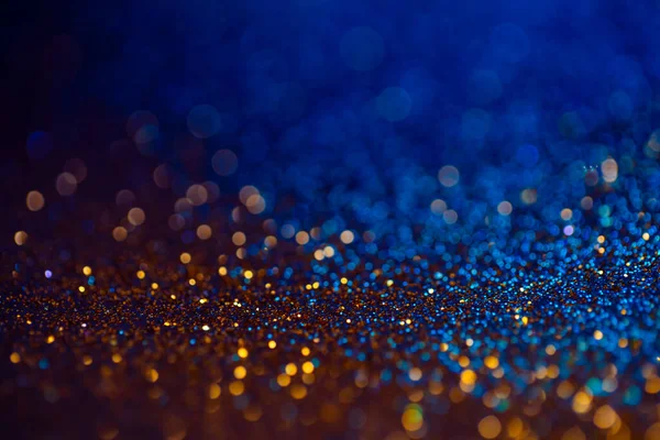 Festlig bokeh glittrar bakgrund, abstrakt suddig bakgrund med cirklar, modern design overlay med gnistrande glimtar. Blå och gyllene bakgrund glittrande gnistor med glöd effekt. — Stockfoto