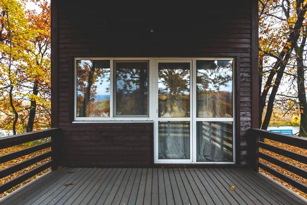 Wooden house exterior. Wooden terrace with big glass door.