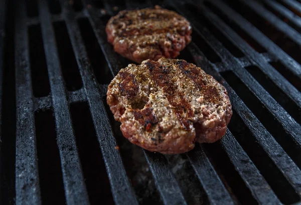 Grilling beef patty for burger on gas grill.