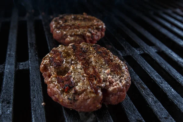 Grilling beef patty for burger on gas grill.