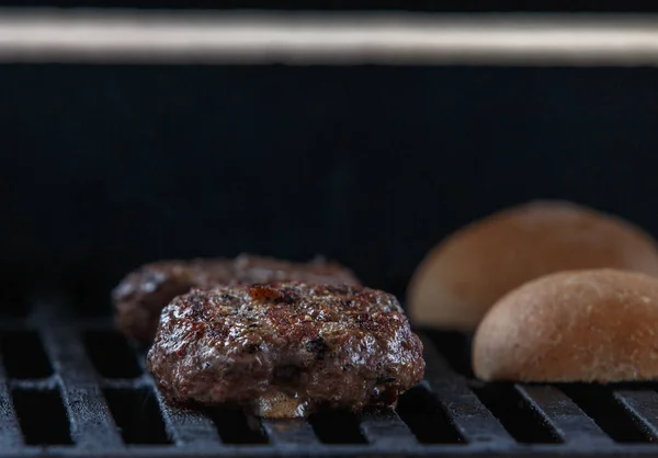 Grilling beef patty for burger on gas grill.