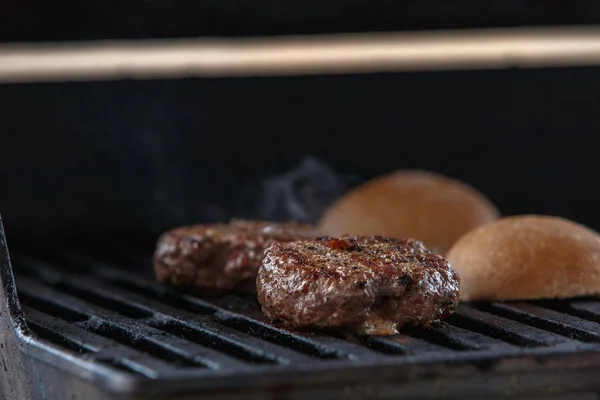 Grilling beef patty for burger on gas grill.