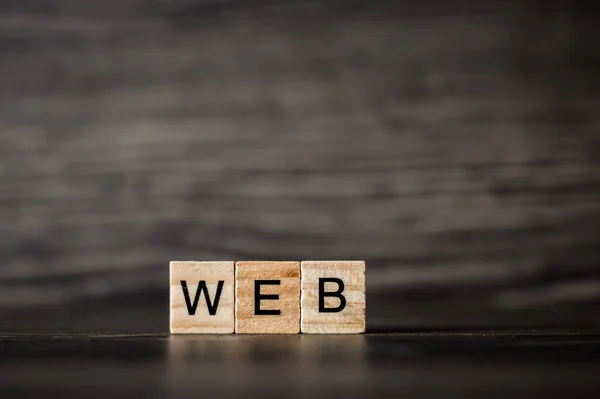 A palavra web, que consiste em um cubos de madeira claros em uma madeira escura — Fotografia de Stock