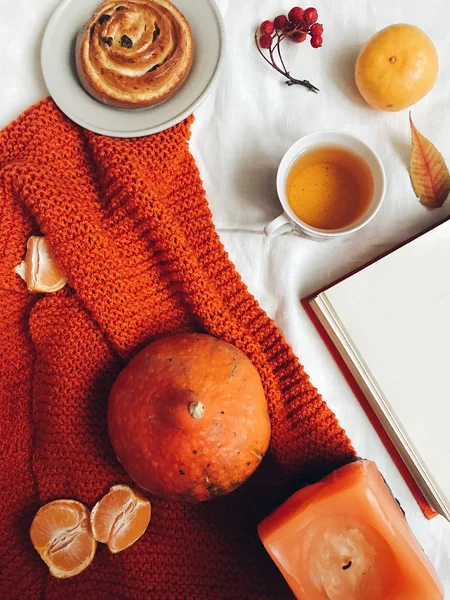 Autumn flat lay. Thanksgiving background with pumpkin, cookie, mandarins, rowan, notebook, cup of tea, candle and leaves. Top view.