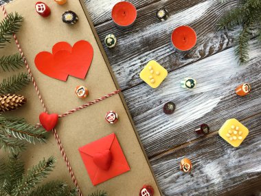 Romantik süslemeleri ile Sevgililer günü kompozisyon: hediye kutusu, mumlar, tatlılar ve kırmızı kalpler ahşap arka plan üzerinde. Kış düz yatıyordu, üstten görünüm. Aşk veya tebrik kavramı. 