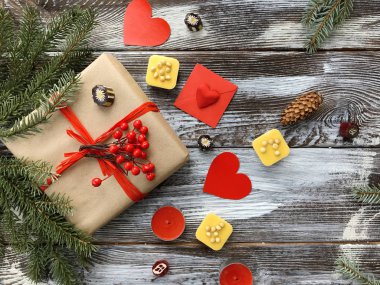 Romantik süslemeleri ile kış kompozisyon: hediye kutusu, mumlar, tatlılar ve kırmızı kalpler ahşap arka plan üzerinde. Sevgililer günü düz yatıyordu, üstten görünüm. Aşk veya tebrik kavramı. 