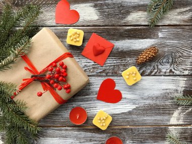 Romantik süslemeleri ile Sevgililer günü kompozisyon: hediye kutusu, mumlar, tatlılar ve kırmızı kalpler ahşap arka plan üzerinde. Kış düz yatıyordu, üstten görünüm. Aşk veya tebrik kavramı. 