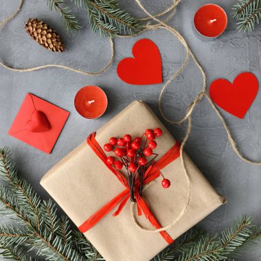 Romantik süslemeleri ile şık kompozisyon: hediye kutusu, mumlar ve kağıt kalpler grunge gri arka plan üzerinde. Kış düz yatıyordu, üstten görünüm. Sevgililer günü kartı.