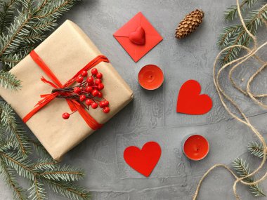 Romantik süslemeleri ile şık kış kompozisyon: hediye kutusu, mumlar ve kağıt kalpler grunge gri arka plan üzerinde. Kış düz yatıyordu, üstten görünüm. Sevgililer günü kartı.