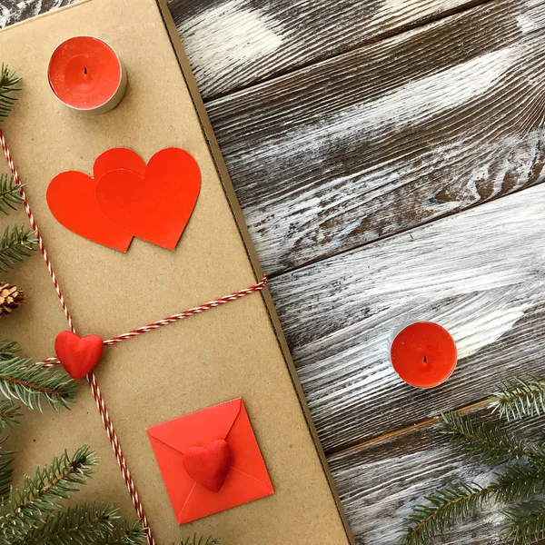 Sevgililer günü düzen romantik süslemeleri ile: hediye kutusu, mumlar ve kırmızı kalpler ahşap arka plan üzerinde. Kış düz yatıyordu, üstten görünüm. Aşk veya tebrik kavramı. 