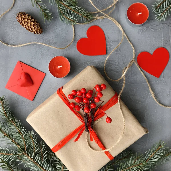 Romantik süslemeleri ile şık kompozisyon: hediye kutusu, mumlar ve kağıt kalpler grunge gri arka plan üzerinde. Kış düz yatıyordu, üstten görünüm. Sevgililer günü kartı.