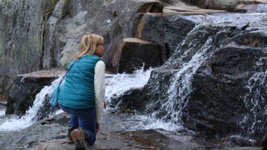 Bayan turist Tahoe Gölü 'ndeki küçük bir şelalenin sonbahar manzarasının tadını çıkarıyor.