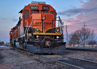 Colorful early morning clouds in the background of an train engine on the siding