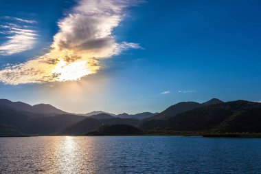 Güneş ışınları bulutlar ve dağ yollarını olun. İşkodra Gölü, Karadağ.