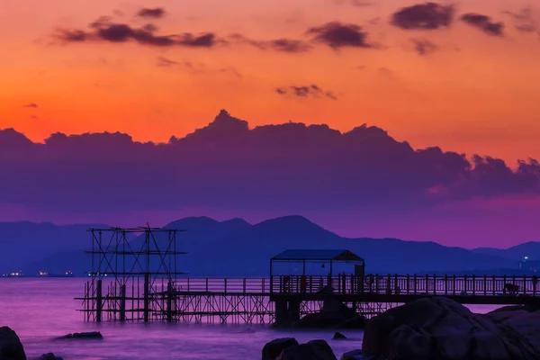 Mor bir gün batımı ışınlarının kıyı bölgesinde. Arka planda Dağları'nın siluetleri görülebilir. 