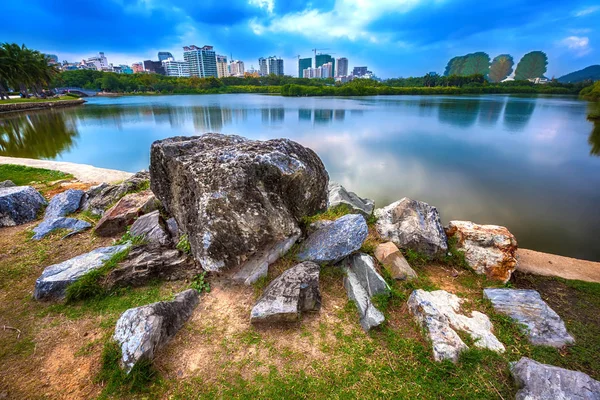 Pitoresk taş şehir binaların zemin karşı parkta gölet önünde. Bailu Park, Sanya, Hainan, Çin.