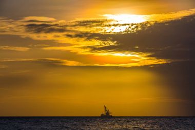 Yüzer petrol platformunda deniz günbatımı. Hainan, Çin.