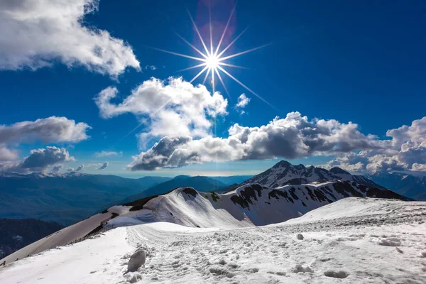 光線の星 明確な雲と青い空のように明るい太陽の下で晴天の上部に雪で覆われたゲレンデ — ストック写真