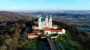 Bielany, Krakow, Polonya, hava 4k video Vistula Nehri ve uzak Cracow şehir içinde belgili tanımlık geçmiş görünümünü ile kışın günbatımı ışıkta Hill'de tahtaya Camaldolese Manastırı ve Barok Kilisesi