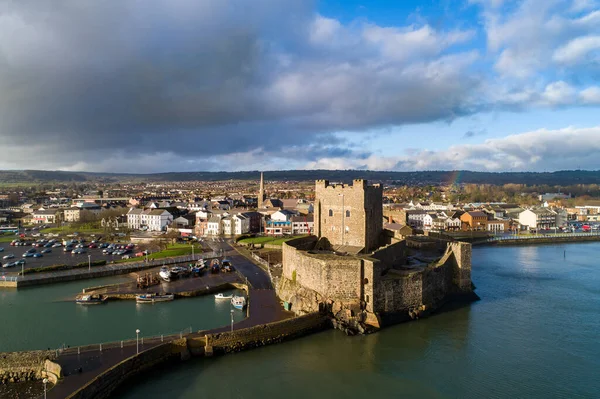Ortaçağ Norman Kalesi, Carrickfergus 'ta tekne rampası ve dalga kırıcısı olan liman Belfast, Kuzey İrlanda, İngiltere yakınlarında. Kışın gün batımında hava manzarası. Kasaba ve fırtınalı bulutlar arka planda