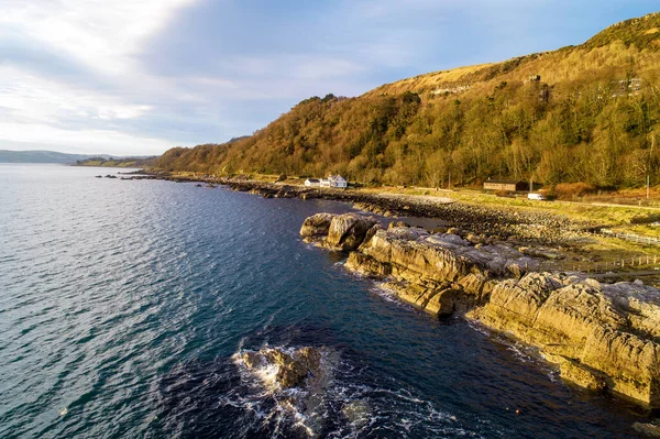 Northern Ireland, UK. Atlantic coast,  Garron Point rocks and Antrim Coast Road, a.k.a. Causeway Costal Route. One of the most scenic coastal roads in Europe. Aerial view in sunrise ligh