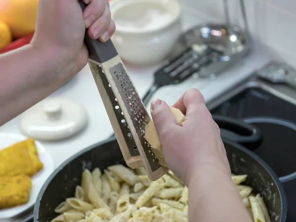 Pasta with cheese. Frying pan with food on the stove.