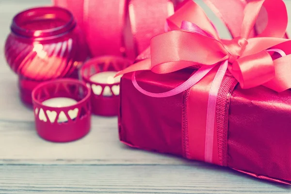 Красная подарочная коробка с лентой, окруженная свечами . — стоковое фото