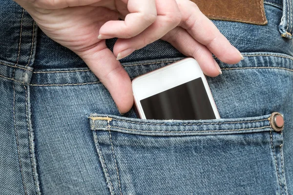 The hand pulls the phone out of the jeans pocket.