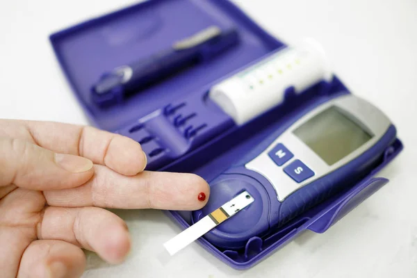 Ein medizinischer Test, bei dem ein Tropfen Blut auf den Zuckerspiegel überprüft wird. — Stockfoto