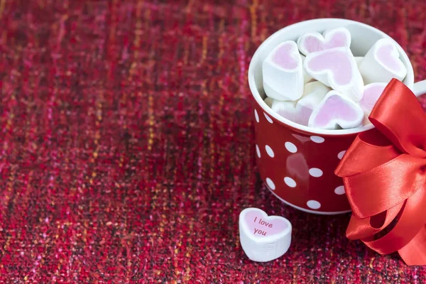Rózsaszín marshmallow hazugság a pöttyös piros csészében. — Stock Fotó