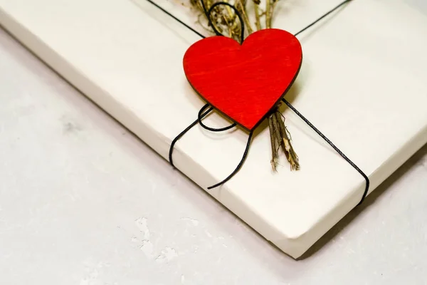 Подарункова коробка ремісничого паперу пов'язана мереживом. Дерев'яне червоне серце . — стокове фото