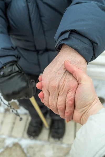 A young woman holds an elderly man by the hand. Retired with a w — Stock Photo, Image
