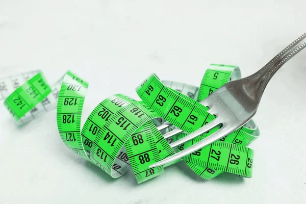 De meetband is groen, gewikkeld rond een stekker liggend op een wh — Stockfoto