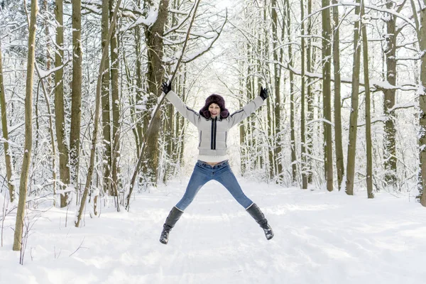 一个女孩在树林里跳起来。很多雪. — 图库照片