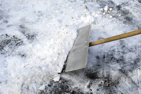Il bidello pulisce la neve sulla strada con una pala . — Foto Stock