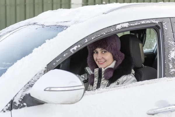 一个女孩开车时坐在一辆白色的小汽车里。冬天, 白天. — 图库照片