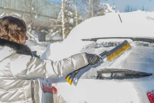 那女孩正在从雪地上刷汽车的挡风玻璃。无线 — 图库照片