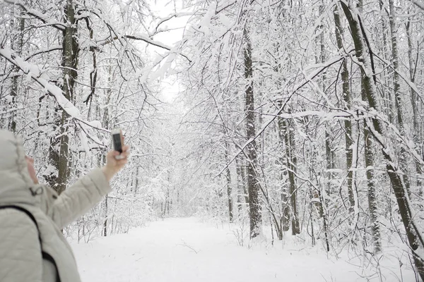 一个女人站在树林里, 在电话里做自拍. — 图库照片