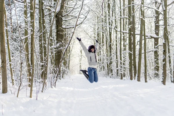 一个女孩在树林里跳起来。很多雪. — 图库照片