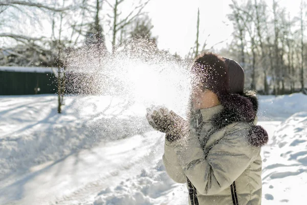 一个女人手里拿着一把雪, 吹着它。无线 — 图库照片